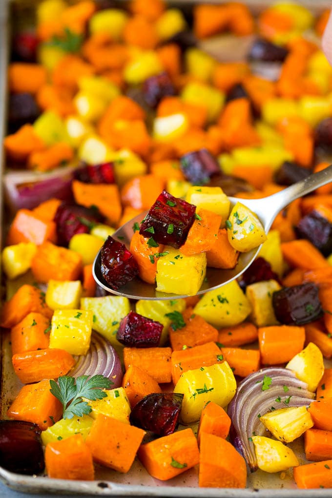 Roasted Root Vegetables Recipe | Roasted Sweet Potatoes | Roasted Beets | Roasted Carrots #carrots #beets #vegetables #sweetpotatoes #fall #parsnips #sidedish #edsug #cleaneating #healthy A spoon serving up a portion of roasted vegetables.