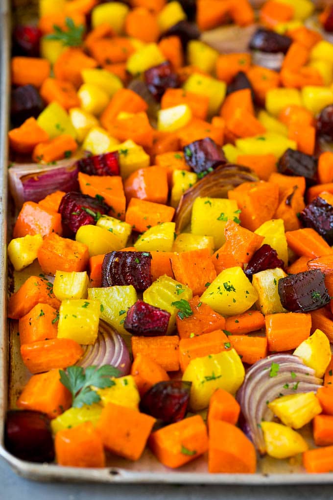 Roasted Root Vegetables Recipe | Roasted Sweet Potatoes | Roasted Beets | Roasted Carrots #carrots #beets #vegetables #sweetpotatoes #fall #parsnips #sidedish #edsug #cleaneating #healthy Roasted root vegetables on a sheet pan, topped with chopped parsley.