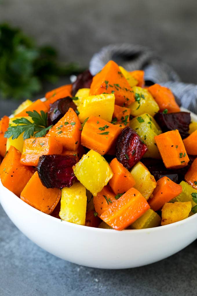 Roasted Root Vegetables Recipe | Roasted Sweet Potatoes | Roasted Beets | Roasted Carrots #carrots #beets #vegetables #sweetpotatoes #fall #parsnips #sidedish #edsug #cleaneating #healthy A bowl of diced roasted root vegetables topped with parsley.