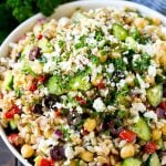 Farro salad made with cuucmber, feta cheese, olives and peppers, topped with parsley.