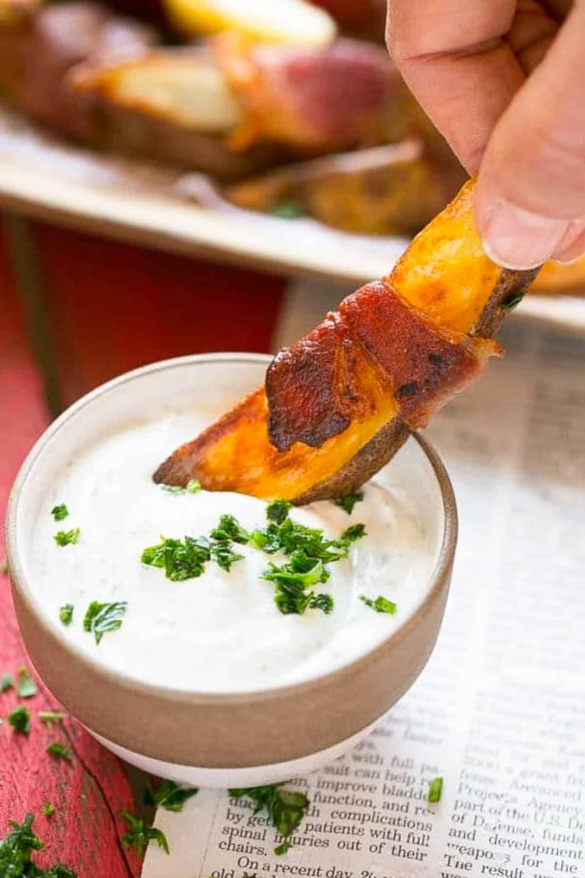 Bacon Wrapped Potato Wedges Recipe | Best Potato Wedges | Bacon Wrapped French Fries | Bacon Potato Wedges #bacon #potato #fries #dinner #edsug A hand putting bacon wrapped potatoes into ranch dip.