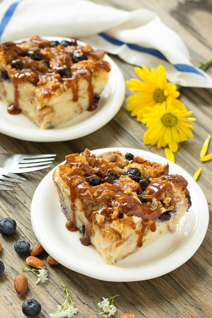 Blueberry Bread Pudding Recipe | Blueberry Bread Pudding | Easy Bread Pudding #blueberry #breadpudding #dessert #edsug Two pieces of blueberry bread pudding on plates with salted caramel on top.