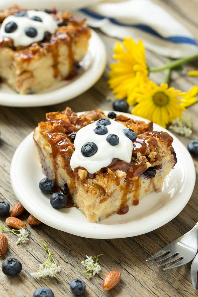 Blueberry Bread Pudding Recipe | Blueberry Bread Pudding | Easy Bread Pudding #blueberry #breadpudding #dessert #edsug Slices of bread pudding on plates, topped with caramel and fresh berries.
