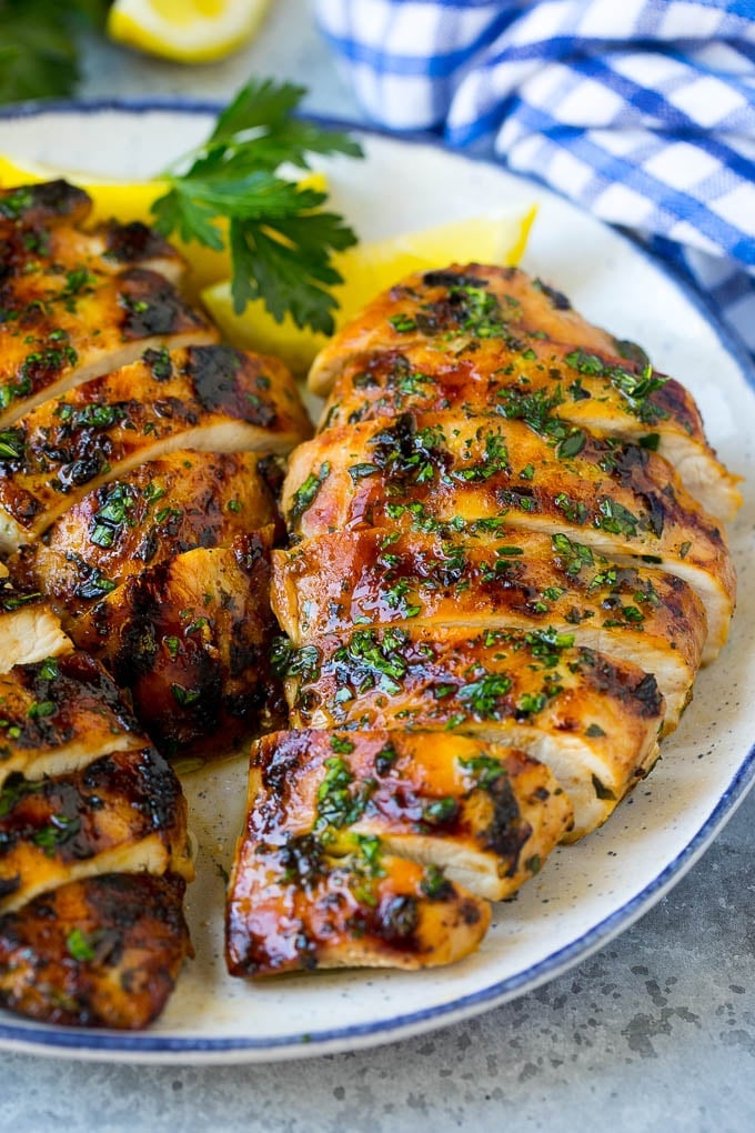 Grilled Chicken Breast Recipe | Marinated Chicken Breast | Chicken Marinade #chicken #grilling #marinade #summer #dinner #edsug Sliced grilled chicken breast garnished with herbs and lemon.