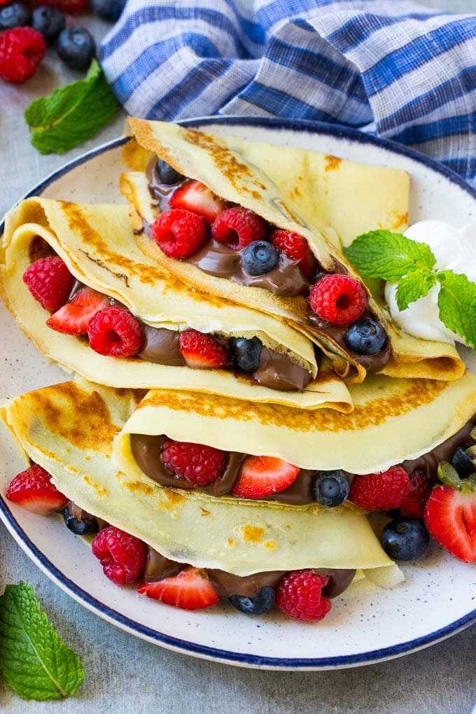Nutella Crepes Recipe | Easy Crepes Recipe | Blender Crepes | Berry Crepes #crepes #nutella #nutellacrepes #blendercrepes #breakfast #edsug A platter of crepes served with whipped cream.