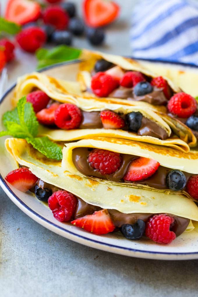 Nutella Crepes Recipe | Easy Crepes Recipe | Blender Crepes | Berry Crepes #crepes #nutella #nutellacrepes #blendercrepes #breakfast #edsug A plate of Nutella crepes with strawberries, blueberries and raspberries.