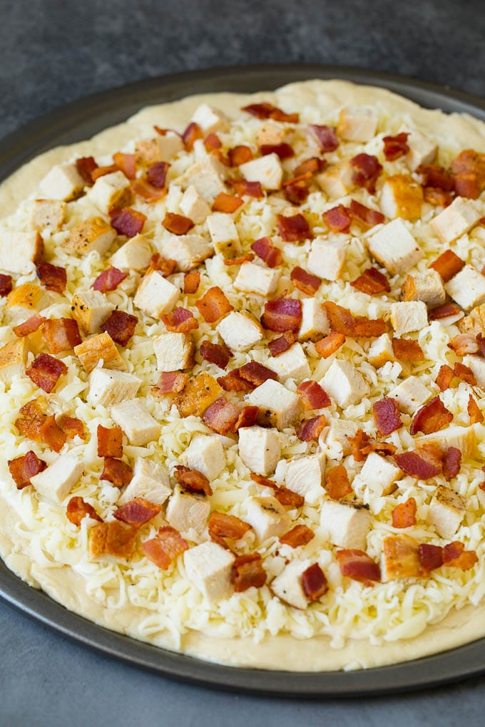 A crust topped with sauce, shredded cheese and meat.