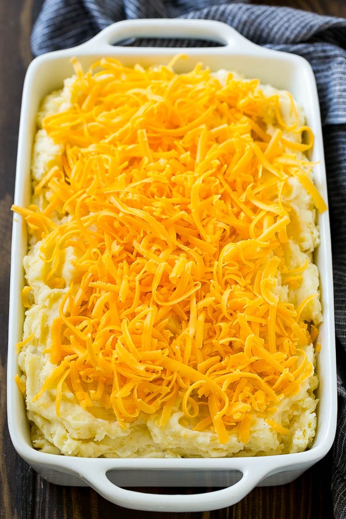Loaded Mashed Potato Casserole Recipe | Loaded Potatoes | Bacon Mashed Potatoes | Thanksgiving Mashed Potatoes #potatoes #bacon #cheese #casserole #Thanksgiving #dinner #edsug Mashed potatoes in a casserole dish, topped with shredded cheese.