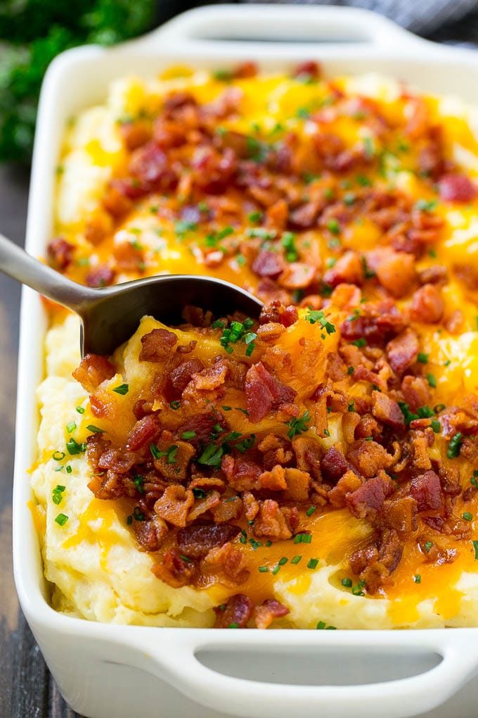 Loaded Mashed Potato Casserole Recipe | Loaded Potatoes | Bacon Mashed Potatoes | Thanksgiving Mashed Potatoes #potatoes #bacon #cheese #casserole #Thanksgiving #dinner #edsug A dish of loaded mashed potato casserole with a serving spoon in it.
