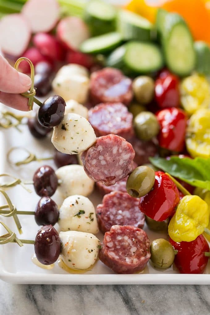 Antipasto Skewers Recipe | Easy Antipasto | Best Antipasto #antipasto #skewers #appetizer #edsug A hand holding up a skewer of salami, cheese and olives.