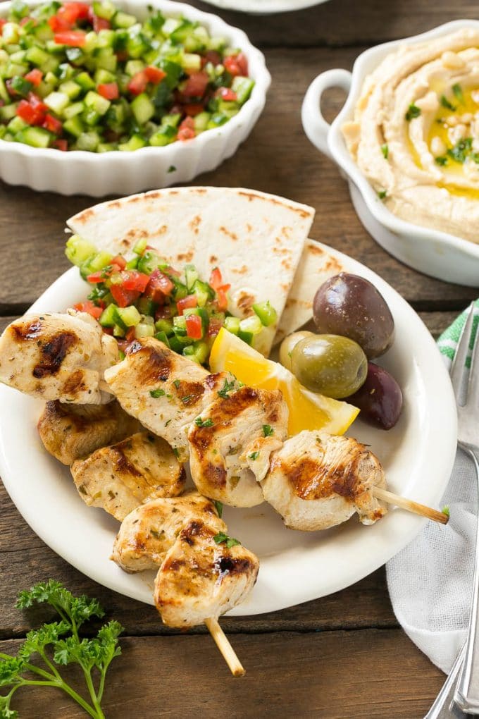 Greek Chicken Souvlaki Recipe | Easy Greek Chicken | Chicken Souvlaki | Greek Chicken Skewers | Easy Greek Chicken Skewers #chicken #kabobs #glutenfree #keto #lowcarb #grilling #edsug A plate of skewers with olives and pita bread.