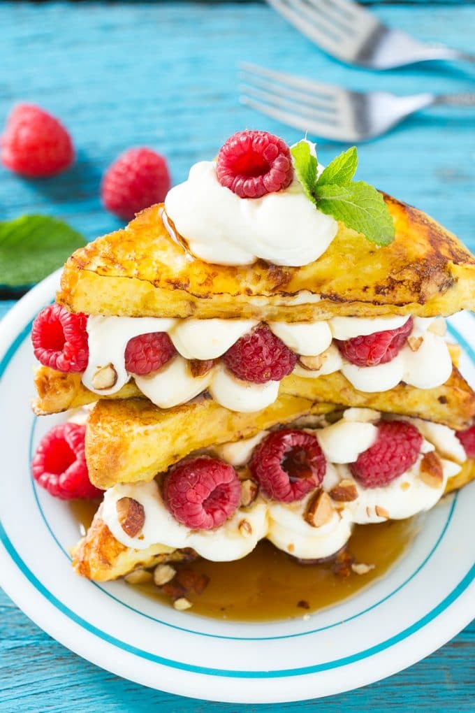 Stuffed French Toast | Cream Cheese Stuffed French Toast | French Toast Recipe #frenchtoast #raspberry #creamcheese #breakfast #brunch #edsug A plate of cooked brioche filled with cream cheese, berries and almonds.