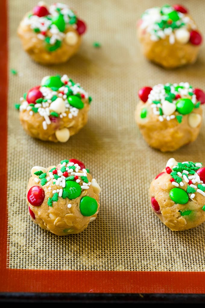 Christmas Monster Cookies Recipe | Oatmeal Cookies | Peanut Butter Cookies | M&M's Cookies #baking #cookies #dessert #peanutbutter #chocolate #edsug #christmas #sprinkles Balls of cookie dough on a baking sheet.