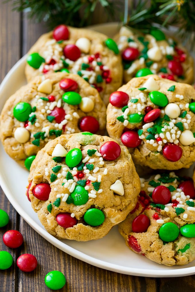 Christmas Monster Cookies Recipe | Oatmeal Cookies | Peanut Butter Cookies | M&M's Cookies #baking #cookies #dessert #peanutbutter #chocolate #edsug #christmas #sprinkles A plate of Christmas monster cookies which are decorated with M&M's, white chocolate and sprinkles.