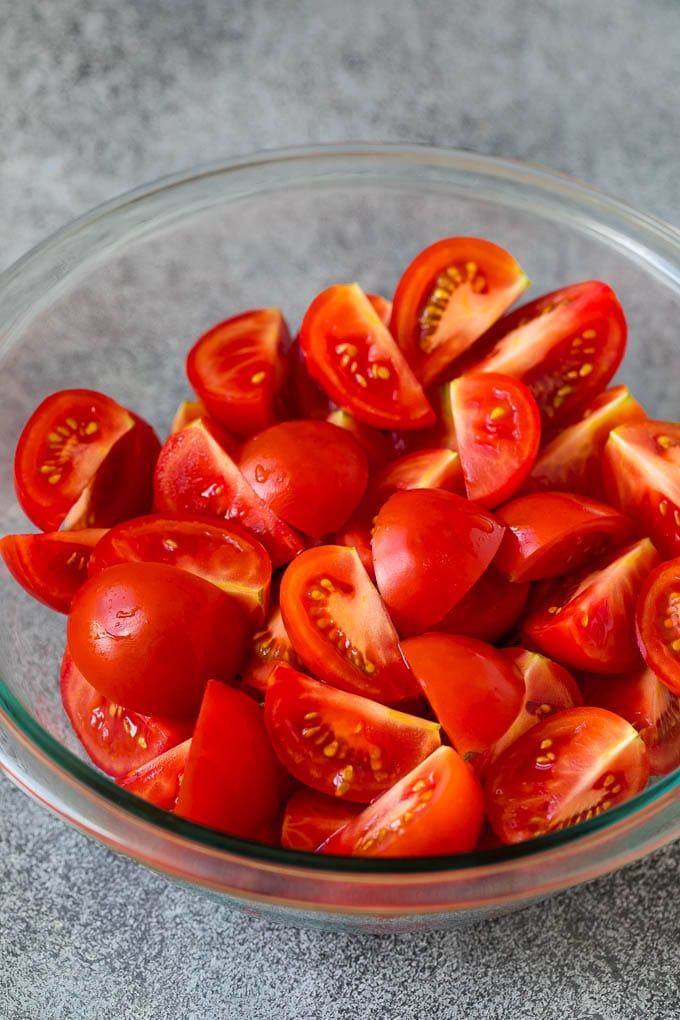 Caprese Salad Recipe | Tomato Salad #salad #tomato #mozzarella #cheese #basil #caprese #summer #edsug Quartered tomatoes in a bowl.