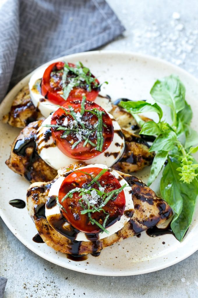 Chicken Caprese Recipe | Grilled Chicken #chicken #caprese #grilling #dinner #tomato #basil #edsug Grilled chicken on a serving plate topped with sliced tomato and cheese.