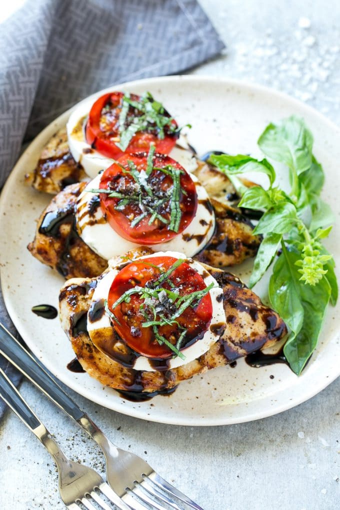 Chicken Caprese Recipe | Grilled Chicken #chicken #caprese #grilling #dinner #tomato #basil #edsug A plate of caprese chicken breasts topped with fresh mozzarella cheese, tomatoes and basil.