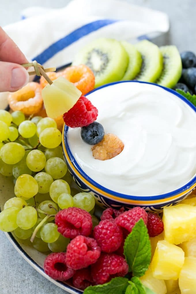 Cream Cheese Fruit Dip | Fruit Recipe | Fruit Dip #fruit #dip #creamcheese #snack #dessert #edsug A skewer of berries going into a bowl of fruit dip.