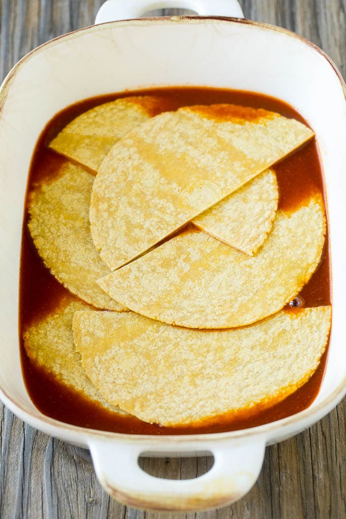 Chicken Enchilada Casserole Recipe | Chicken Enchiladas | Easy Casserole Recipe | Enchilada Casserole #chicken #casserole #enchiladas #cheese #beans #dinner #edsug Corn tortillas and enchilada sauce in a casserole dish.