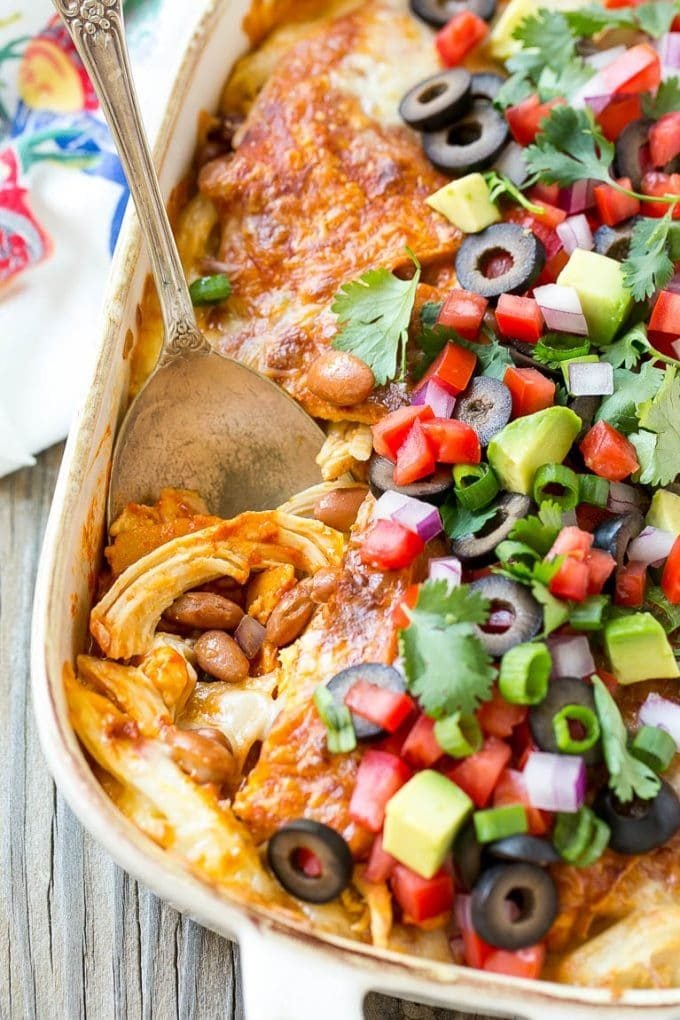 Chicken Enchilada Casserole Recipe | Chicken Enchiladas | Easy Casserole Recipe | Enchilada Casserole #chicken #casserole #enchiladas #cheese #beans #dinner #edsug A chicken enchilada casserole with a serving spoon in it.