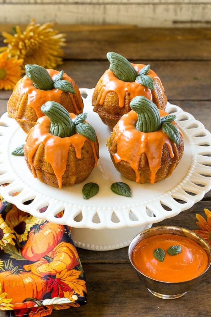 Pumpkin Spice Cake Recipe | Pumpkin Cake | Easy Pumpkin Cake | Thanksgiving Dessert #thanksgiving #pumpkin #cake #pumpkincake #spicecake #dessert #edsug #holiday Pumpkin spice cake topped with orange glaze and fondant decorations on a serving platter.