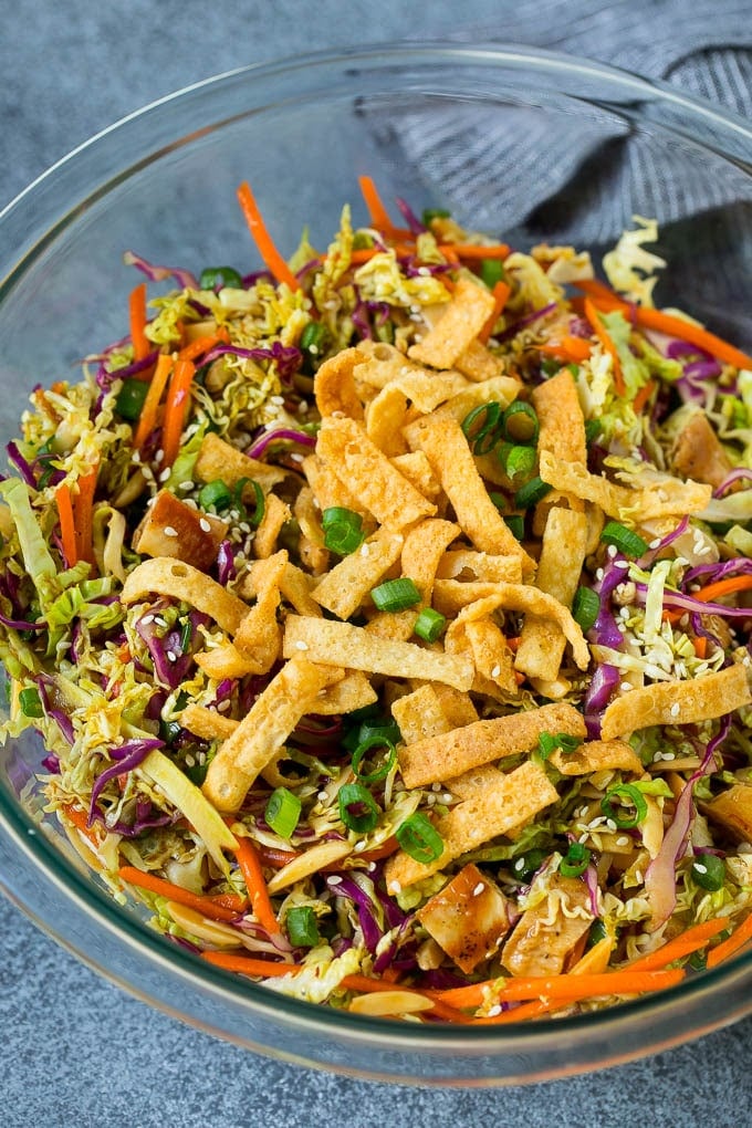 Chinese Chicken Salad Recipe | Asian Chicken Salad #salad #chicken #chickensalad #cabbage #lunch #dinner #edsug A bowl of Chinese chicken salad topped with wontons and sesame seeds.