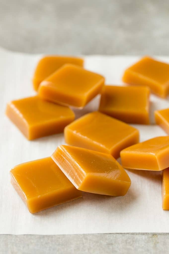 Microwave Caramels with Sea Salt Recipe | Homemade Caramels | Sea Salt Caramel | Homemade Candy #candy #caramels #caramel #microwavecaramels #homemade #dessert #edsug Squares of cooked caramel on parchment.