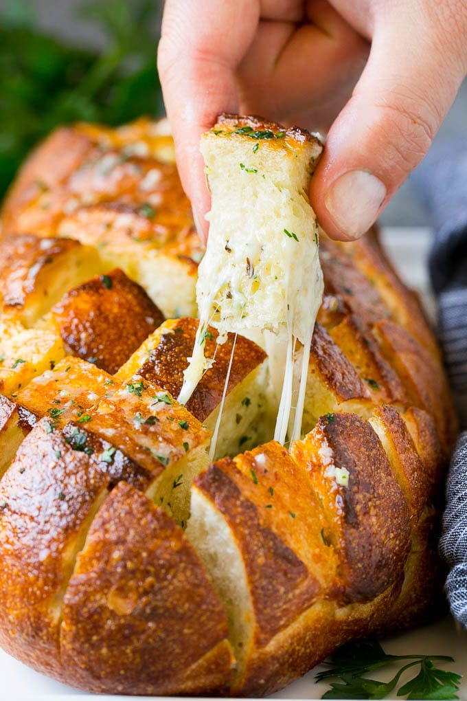 Pull Apart Bread | Garlic Bread | Cheese Bread #bread #garlic #cheese #sidedish #appetizer #edsug A hand grabbing a piece of pull apart bread.