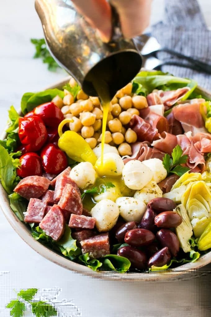 Antipasto Salad Recipe | Italian Salad | Main Course Salad | Antipasto Recipe #salad #salami #italianfood #dinner #lunch #edsug A pitcher of dressing being poured over antipasto salad.