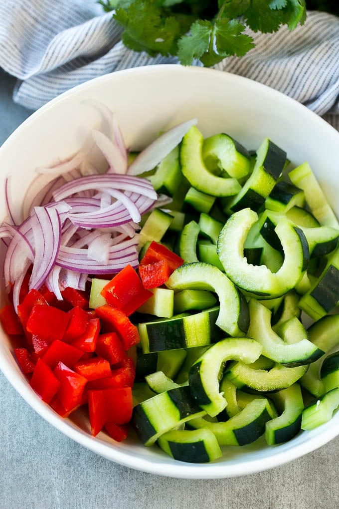 Asian Cucumber Salad Recipe | Sesame Cucumber Salad | Cucumber Salad | Healthy Salad | Healthy Cucumber Recipe #cucumber #cucumbersalad #salad #sidedish #edsug Sliced cucumbers, red peppers and red onion in a serving bowl.