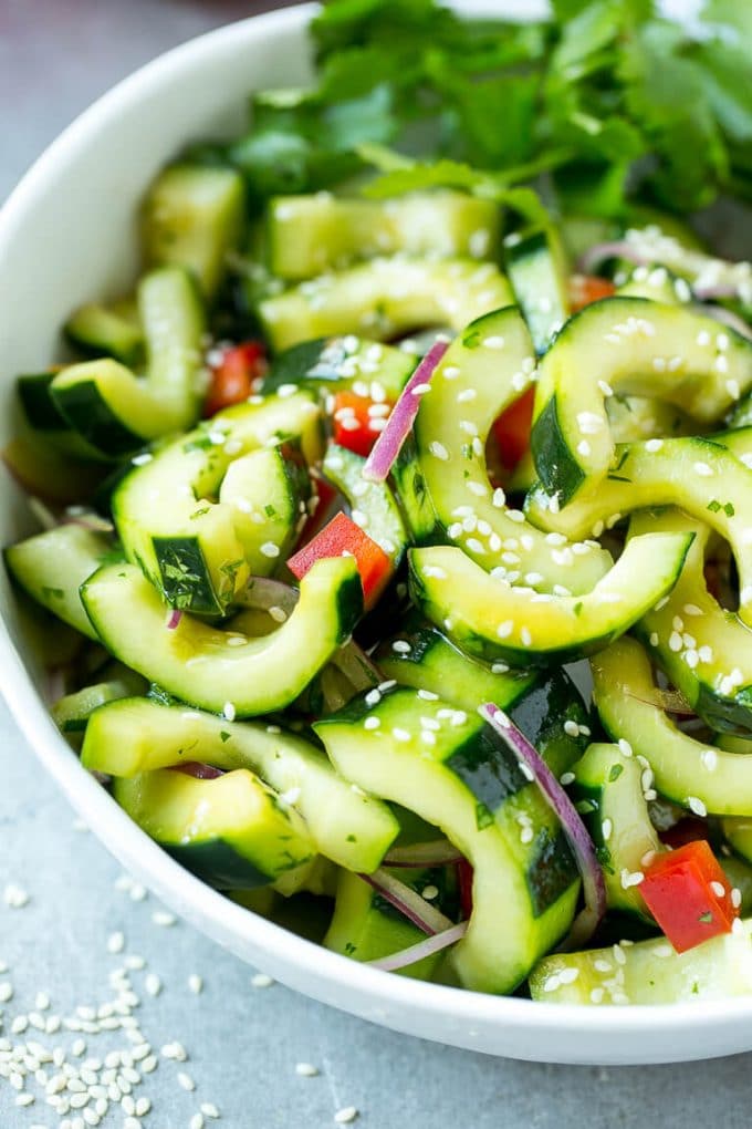 Asian Cucumber Salad Recipe | Sesame Cucumber Salad | Cucumber Salad | Healthy Salad | Healthy Cucumber Recipe #cucumber #cucumbersalad #salad #sidedish #edsug A bowl of Asian cucumber salad with dressing and sesame seeds on top.