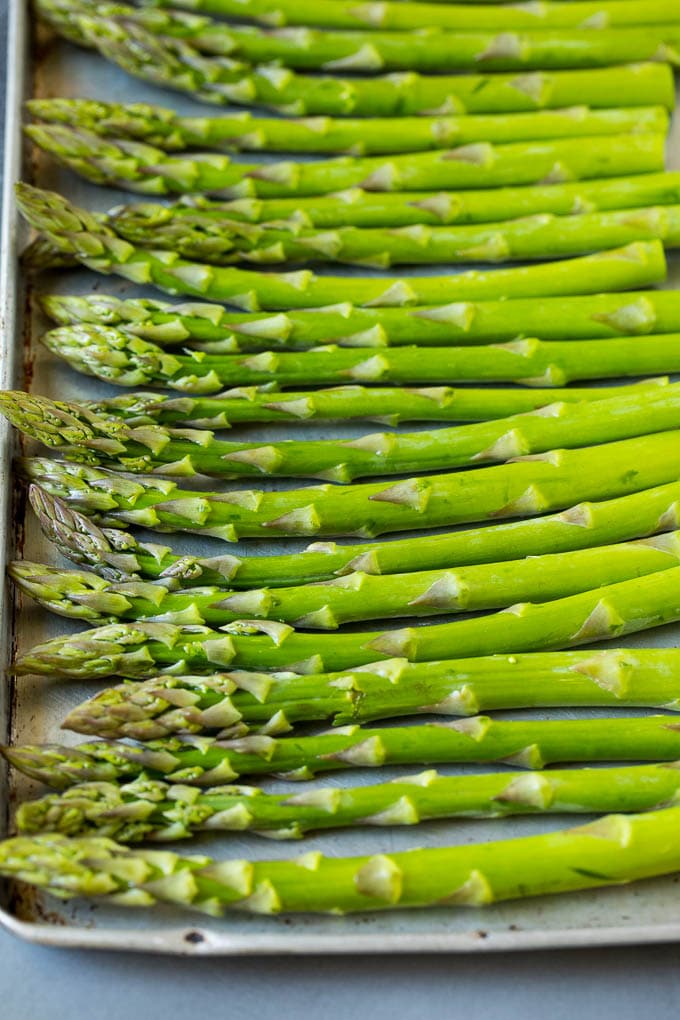 This prosciutto wrapped asparagus is fresh asparagus stalks flavored with savory prosciutto, then broiled to crispy perfection. Fresh stalks on a sheet pan.