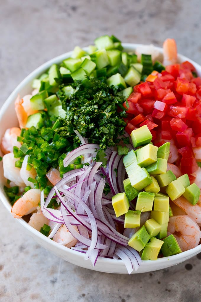 Shrimp Ceviche Recipe | Mexican Shrimp | Marinated Shrimp #shrimp #ceviche #cleaneating #healthy #lowcarb #keto #glutenfree #dinner #appetizer #edsug Prawns, avocado, red onion tomatoes, cilantro, jalapeno and cilantro in a bowl.
