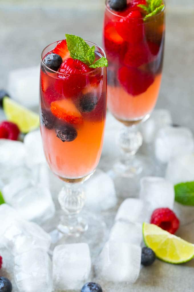 Berry Champagne Punch Recipe | Champagne Cocktail | Lime Cocktail | Berry Punch | Champagne Recipe #champagne #punch #berries #drink #edsug Two champagne flutes filled with berry champagne punch garnished with berries.