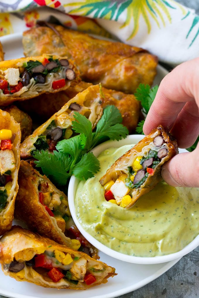 Southwestern Egg Rolls Recipe | Easy Egg Roll Recipe | Mexican Appetizer | Egg Roll Recipe | Southwest Egg Rolls #eggrolls #appetizer #chicken #snack #edsug A southwestern egg roll being dipped into avocado sauce.