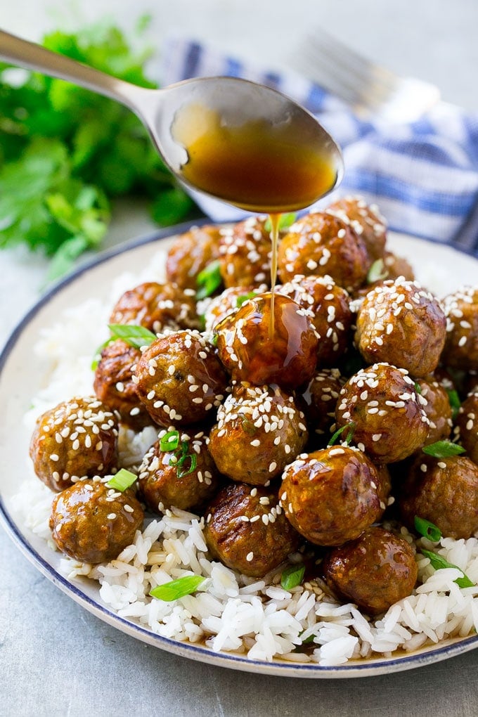 Teriyaki Meatballs Recipe | Asian Meatballs Recipe | Easy Meatball Recipe | Appetizer Meatballs #meatballs #teriyaki #beef #rice #dinner #edsug Teriyaki sauce spooned over a pile of meatballs on a bed of rice.