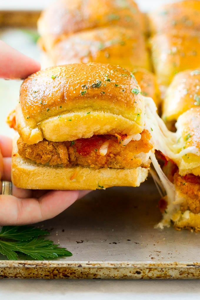 Chicken Parmesan Sliders | Chicken Parmesan Sandwich Recipe | Slider Sandwich Recipe #sliders #chickenparm #chickenparmesan #chickenparmesansliders #dinner #appetizer #edsug A crispy chicken parmesan slider being pulled away by a hand.