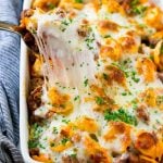 A pan of cheesy baked tortellini with a spoon lifting up a portion.