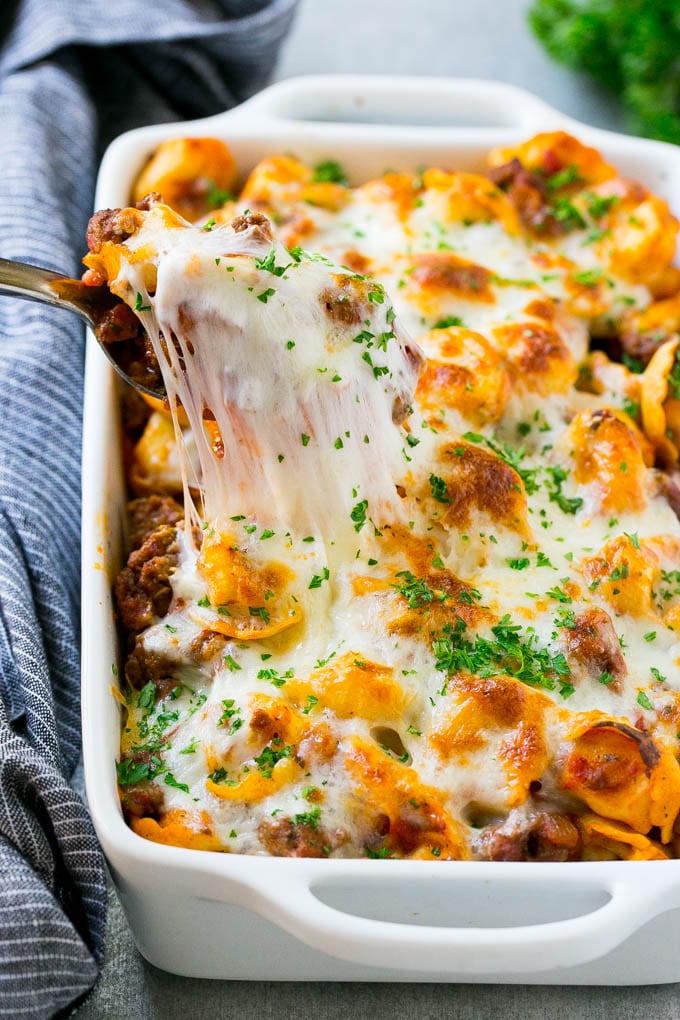 Baked Tortellini with Meat Sauce Recipe | Cheese Tortellini | Tortellini Recipe | Baked Pasta Recipe #tortellini #bakedtortellini #meatsauce #pasta #dinner #edsug A pan of cheesy baked tortellini with a spoon lifting up a portion.