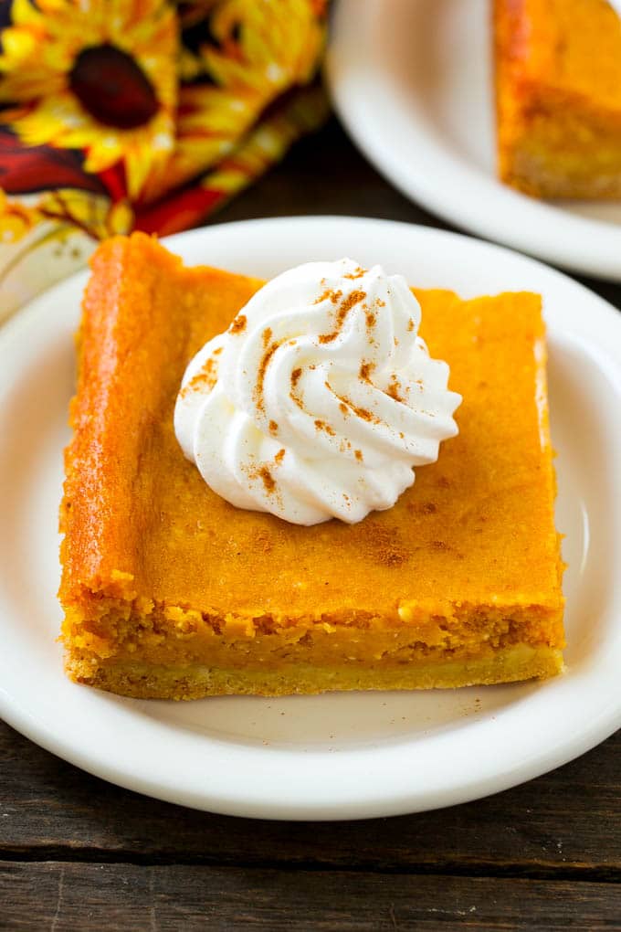 Pumpkin Gooey Butter Cake Recipe | Pumpkin Cake Recipe | Gooey Butter Cake | Pumpkin Dessert | Thanksgiving Dessert #pumpkin #cake #pumpkincake #gooeybuttercake #dessert #edsug A slice of pumpkin gooey butter cake topped with whipped cream.