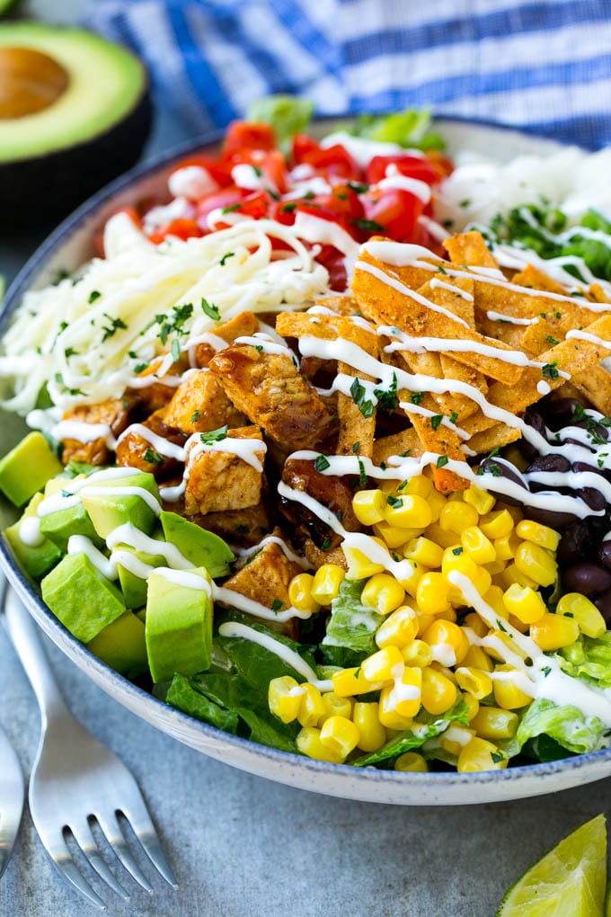 BBQ Chicken Salad Recipe | Chopped BBQ Chicken Salad | CPK Copycat Recipe | California Pizza Kitchen Copycat Recipe | Chicken Ranch Salad #copycat #CPK #BBQchicken #chicken #salad #dinner #edsug A bowl of BBQ chicken salad topped with a drizzle of ranch dressing.