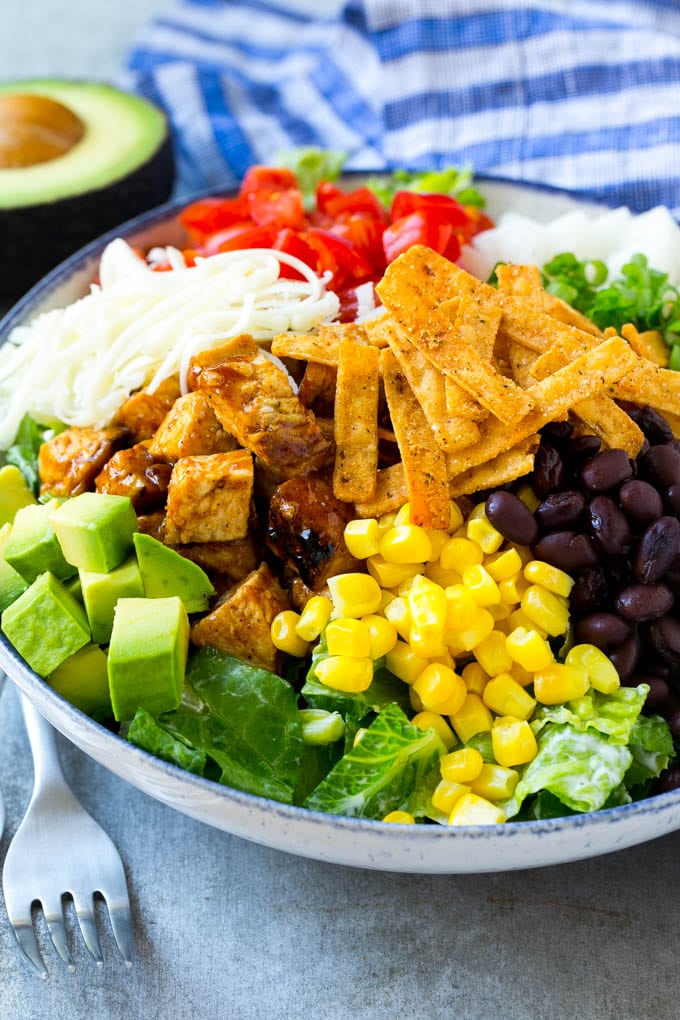 BBQ Chicken Salad Recipe | Chopped BBQ Chicken Salad | CPK Copycat Recipe | California Pizza Kitchen Copycat Recipe | Chicken Ranch Salad #copycat #CPK #BBQchicken #chicken #salad #dinner #edsug A bowl of salad topped with chicken, tortilla strips, black beans, jiacama, avocado and tomatoes.