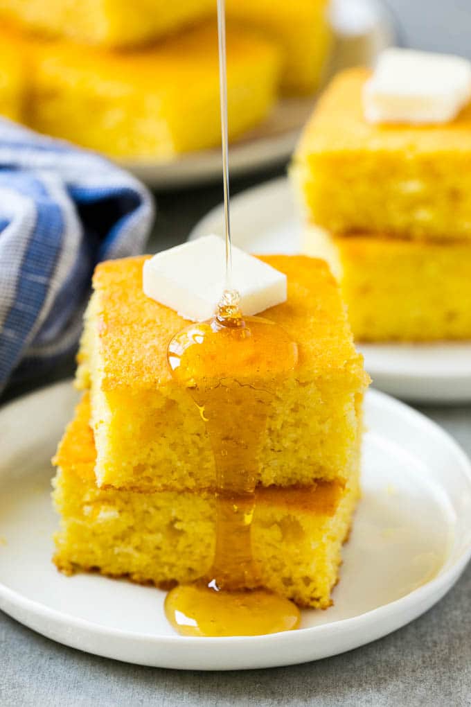 Honey Cornbread Recipe | Buttermilk Cornbread | Easy Cornbread | Homemade Cornbread | Cast Iron Cornbread #cornbread #honey #buttermilk #bread #edsug A stack of cornbread topped with butter and honey
