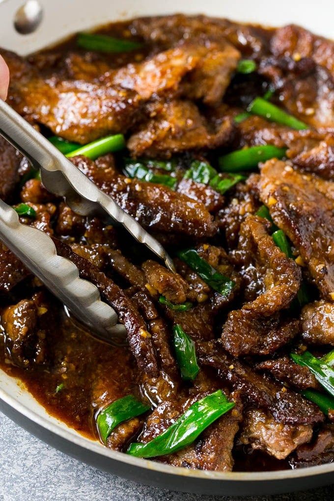 Mongolian Beef Recipe | Asian Beef Recipe | Chinese Beef | Beef Stir Fry #Chinese #Mongolian #Asian #mongolianbeef #beef #edsug #dinner A pan of Mongolian beef with tongs in it.