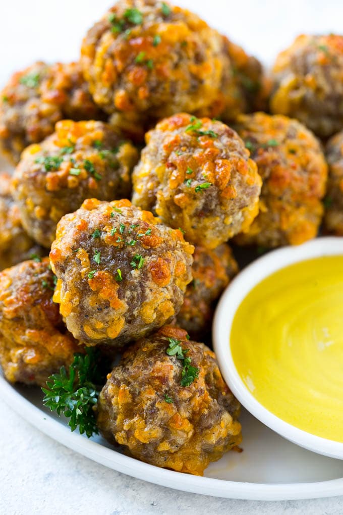 Sausage Cheese Balls Recipe | Sausage Balls Recipe | Bisquick Sausage Balls #sausage #sausageballs #balls #appetizer #cheeseballs #edsug A pile of sausage cheese balls with a side of honey mustard.