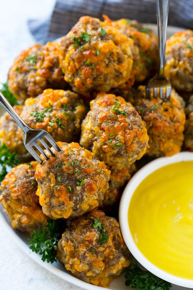 Sausage Cheese Balls Recipe | Sausage Balls Recipe | Bisquick Sausage Balls #sausage #sausageballs #balls #appetizer #cheeseballs #edsug A plate of meatballs with cocktail forks.