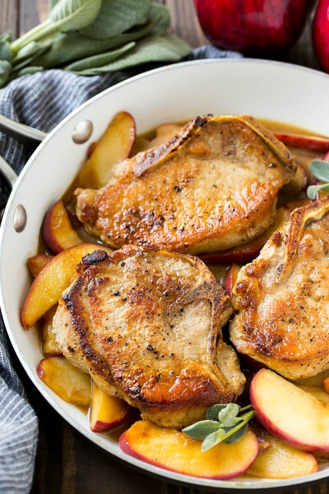 Apple Pork Chops Recipe | Pork Chops with Apples | Cider Pork Chops | Bone In Pork Chops Recipe #pork #porkchops #fall #apple #dinner #edsug A pan of apple pork chops garnished with fresh sage.