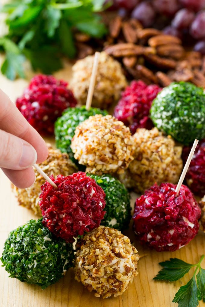 Cheese Ball Bites Recipe | Holiday Cheese Ball Recipe | Pecan Cheese Ball | Cranberry Cheese Ball | Mini Cheese Balls #cheeseball #cheese #appetizer #edsug A hand reaching for an appetizer crusted in dried craberries.