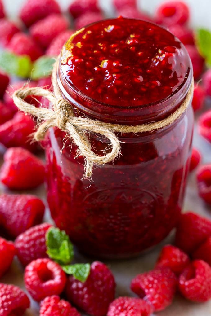 Raspberry Sauce Recipe | Homemade Raspberry Sauce | Raspberry Recipe #raspberries #dessert #edsug A jar of homemade raspberry sauce surrounded by fresh raspberries.