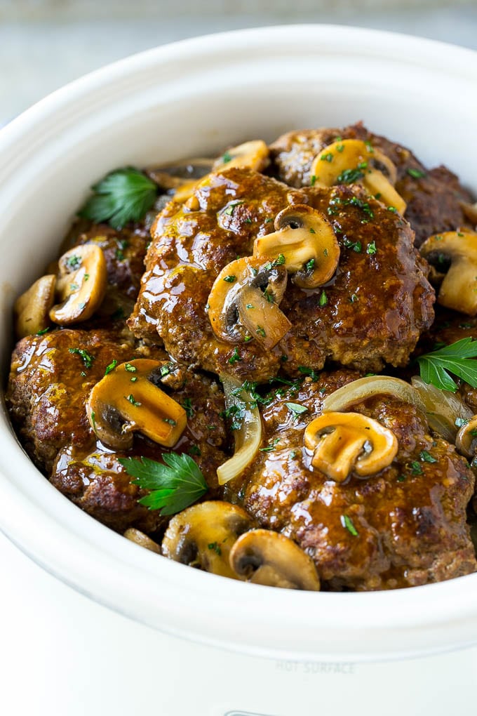 Slow Cooker Salisbury Steak Recipe | Homemade Salisbury Steak | Salisbury Steak from Scratch #steak #beef #salisbury #salisburysteak #slowcooker #crockpot #dinner #edsug A crock pot with hamburger patties, cooked mushrooms and gravy.